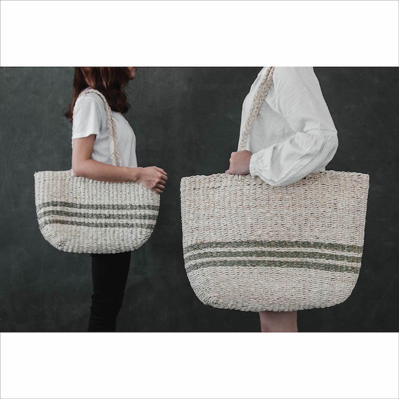 Two women carrying large striped seagrass beach totes.