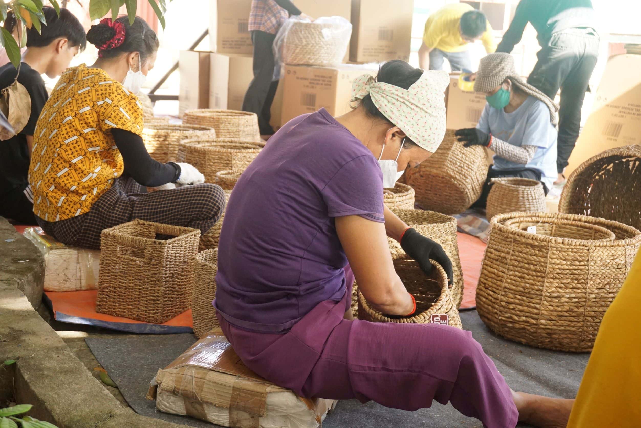 Artisans in Vietnam weaving seagrass baskets by hand, seated together in a workshop.
