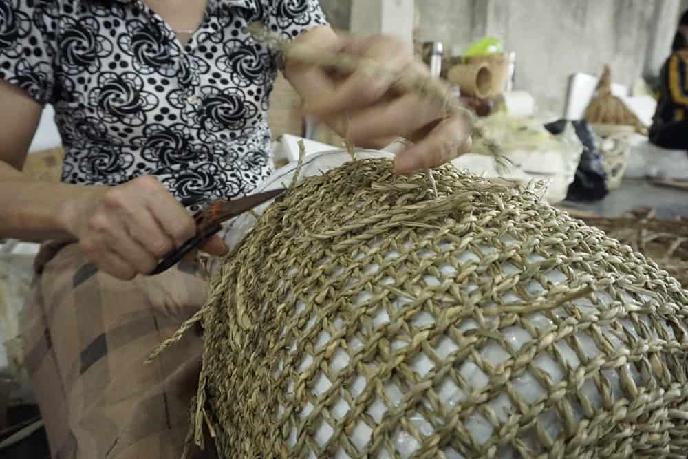 A Viet Trang artisan hand-weaving a seagrass basket in Nga Son, Vietnam.