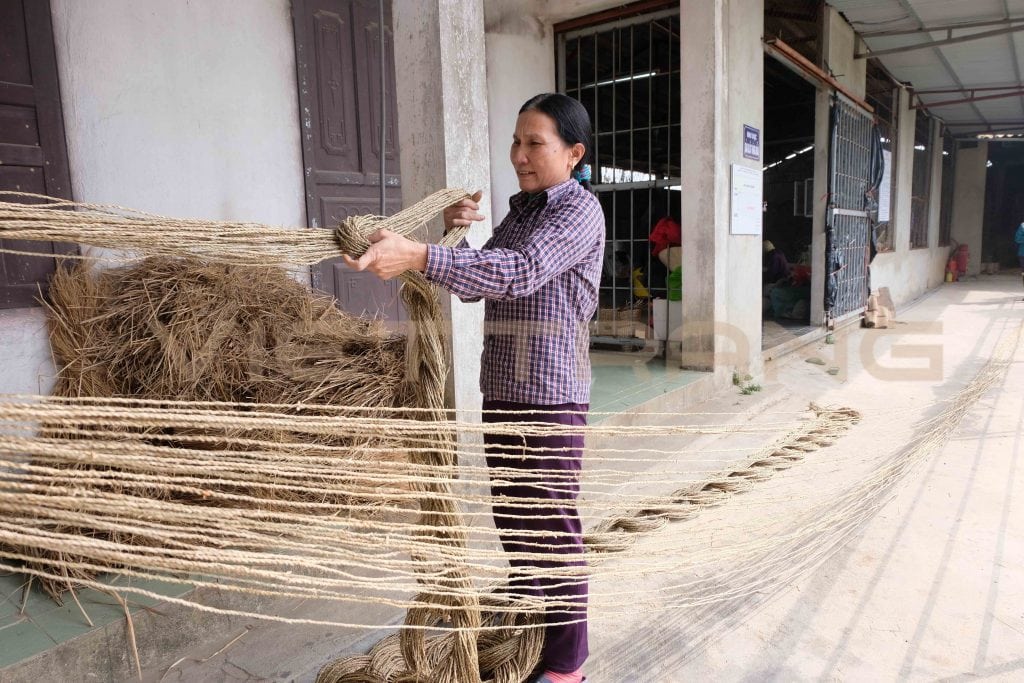 Worker hanging bundles of twisted seagrass rope to dry at a workshop in Nga Son, Vietnam