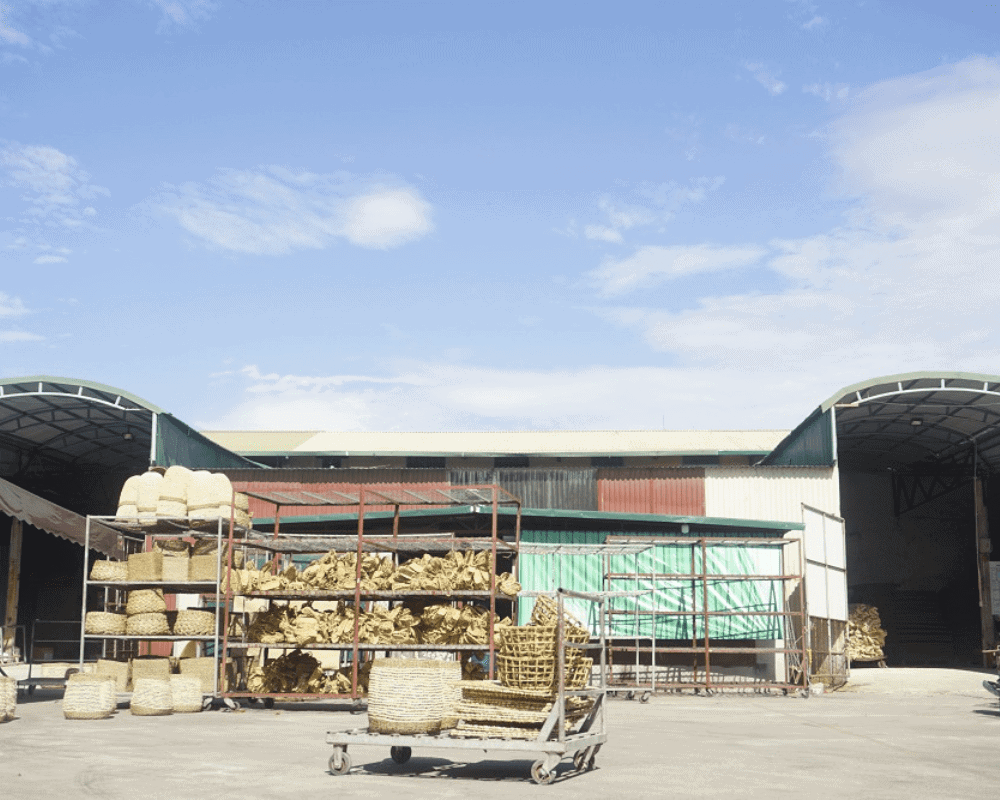 Factory yard stacked with woven goods and pallets under a clear blue sky