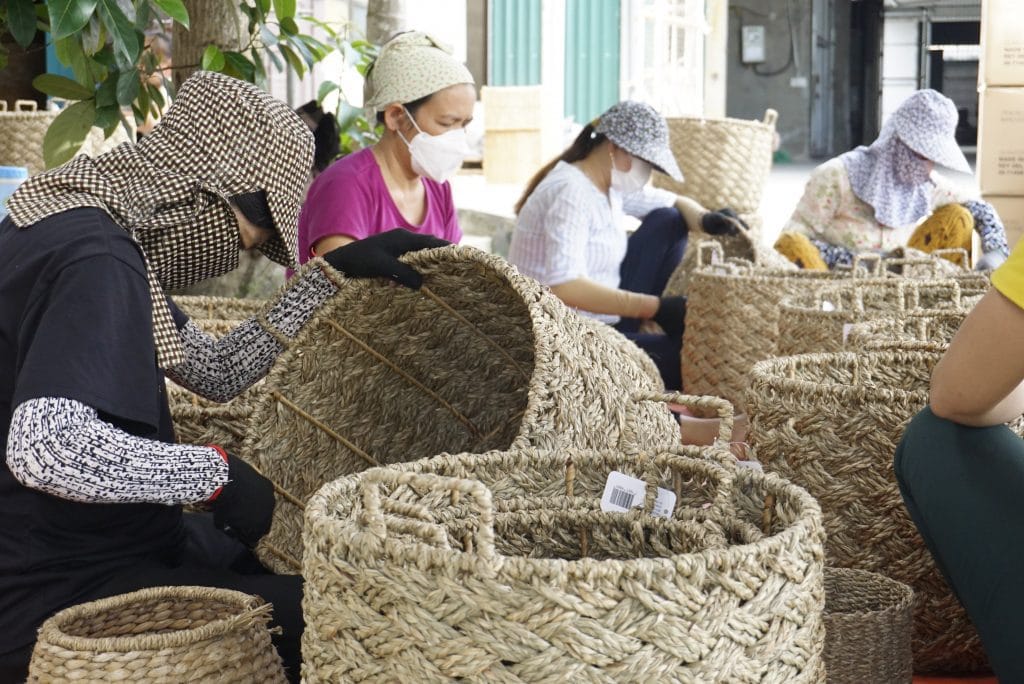 Women weaving natural fiber baskets together in the workshop at Viet Trang in Nga Son, Vietnam.
